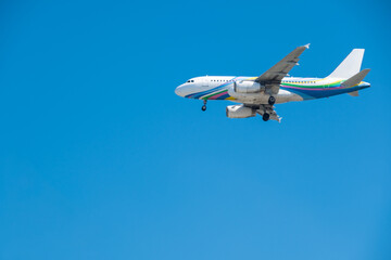 Passenger aircraft with landing gear down, flying in a bright blue sky. on the engines and tail, perfect for travel and transportation concepts