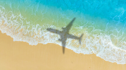 Aerial view of shadow passenger plane silhouette and sandy beach blue sea with waves at sea beach summer vacation sea travel concept	