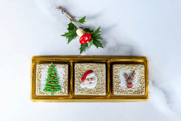 Three Brazilian honey cakes lined up and decorated with marzipan in a Christmas theme.