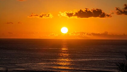 Obraz premium Fiery orb sinks into horizon, painting the sea with golden light