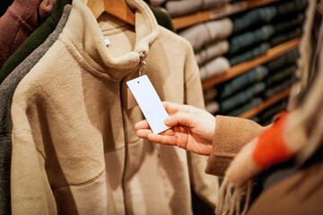 Woman Holding Price Tag on Winter Coat in Store © zhouyilu