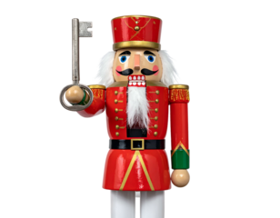 Festive wooden figurine of a soldier in red uniform, holding a key, against a black background