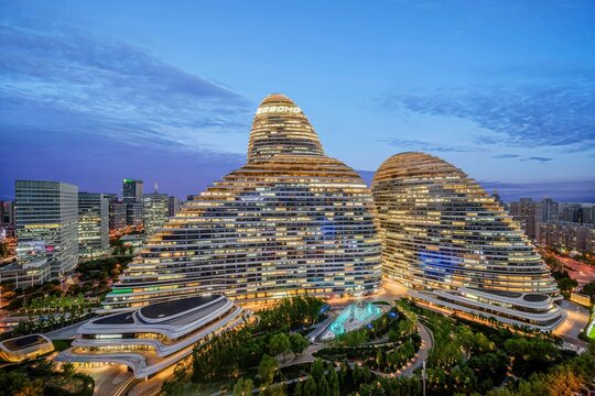 A stunning aerial view of the iconic Beijing Wangjing SOHO complex during twilight, showcasing modern architecture and urban lighting.