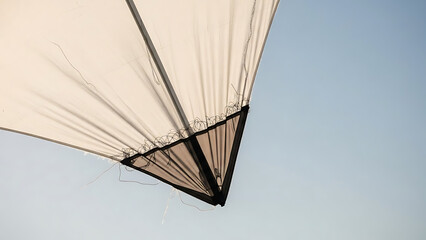 Obraz premium A close-up, low-angle view of a light-colored fabric structure, possibly a sail or umbrella, with prominent folds and lines against a clear blue sky.