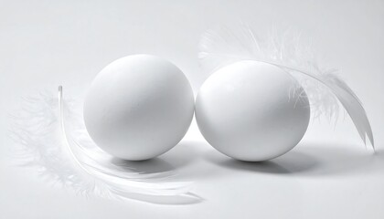 Two white eggs and delicate feathers on a white background.