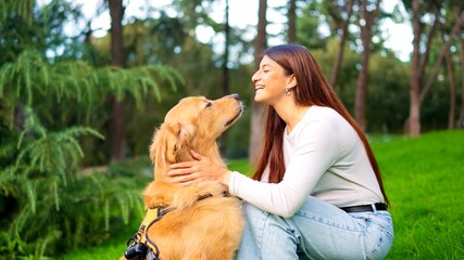 Woman smiling bonding with her golden retriever dog in park