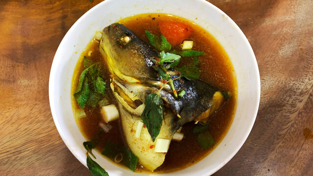 Savory Fish Head Soup with Herbs and Vegetables in a White Bowl called Pindang Patin
