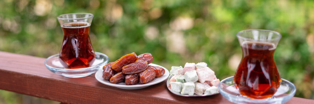 Dry Dates in a bowl and tea in armudu glass. Ramadan kareem.  Outdoor  background.