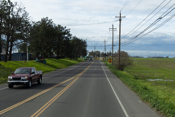 Road scene with vehicles and fields on a cloudy day in a rural area