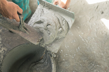 Hand worker mix Cement in bucket plaster construction house site background, Concrete mortar mix sand wet with trowel tool well free space for text