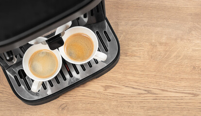 Top view of coffee machine preparing two cups of fresh espresso on wooden table