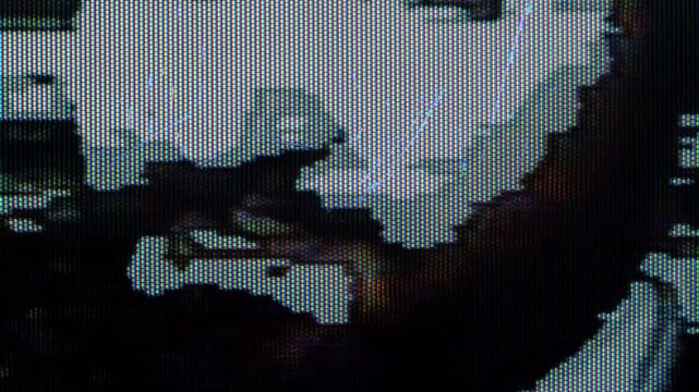 A highly pixelated and distorted image with digital glitch effects, showing abstract shapes and dark tones, resembling a corrupted video feed or a digital art piece.