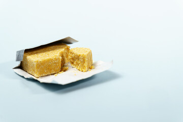 Bouillon cube, partially unwrapped and broken, showing texture used as a convenient flavor enhancer in recipes
