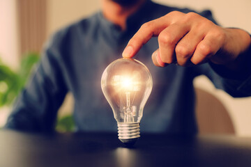 Businessman's hand chooses light bulb or lamp with bright for human resources or leadership and creativity thinking idea motivation or vision and knowledge learning. © Jintana