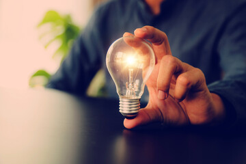 Businessman's hand chooses light bulb or lamp with bright for human resources or leadership and creativity thinking idea motivation or vision and knowledge learning. © Jintana