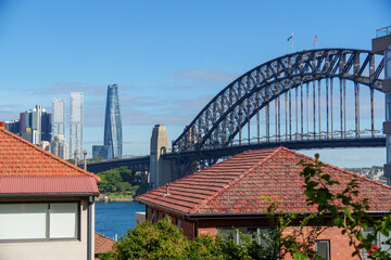 Fototapeta premium Sydney Harbour Bridge connecting city skyline and residential areas, showcasing a blend of architecture and natural beauty on a clear day.