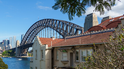 Fototapeta premium Expansive Daytime View of Sydney Harbour Bridge Soaring Above Charming Residential Buildings and a Modern City Skyline