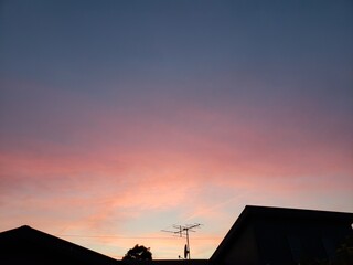 住宅の屋根の上の柔らかいパステルカラーの夕焼け空