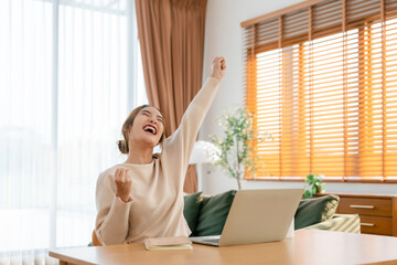 Funny euphoric young asian woman celebrating winning or getting ecommerce shopping offer on computer laptop. Excited happy girl winner looking at notebook celebrating success