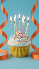 birthday cupcake with lit candles and sprinkles on blue background with orange ribbon streamers, festive party dessert, celebration concept with copy space