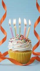 birthday cupcake with lit candles and sprinkles on blue background with orange ribbon streamers, festive party dessert, celebration concept with copy space