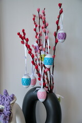 Vase with branch and Easter eggs against white wall