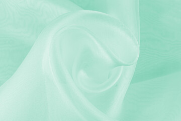 Graceful delicate twisted waves of transparent mint organza. chic festive background. A copy of the space. layout for design