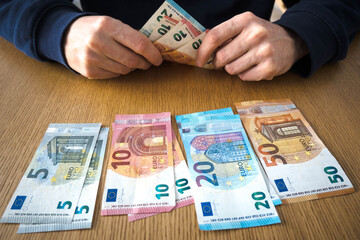 Euro banknotes on the table, men's hands.
