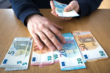 Euro banknotes on the table, men's hands.
