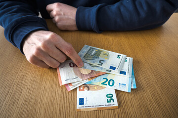 Euro banknotes on the table, men's hands.
