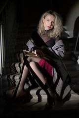A stylish woman in a coat sits on the stairs. Noir style