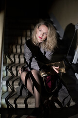 A stylish woman in a coat sits on the stairs. Noir style