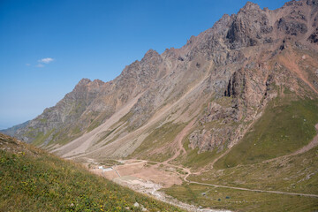 High-altitude mountain pass in the Trans-Ili Alatau range. Gravel road among Tuyuk-Su glaciers and rocky valleys, Tien Shan, Central Asia