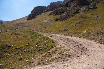 High-altitude mountain pass in the Trans-Ili Alatau range. Gravel road among Tuyuk-Su glaciers and rocky valleys, Tien Shan, Central Asia