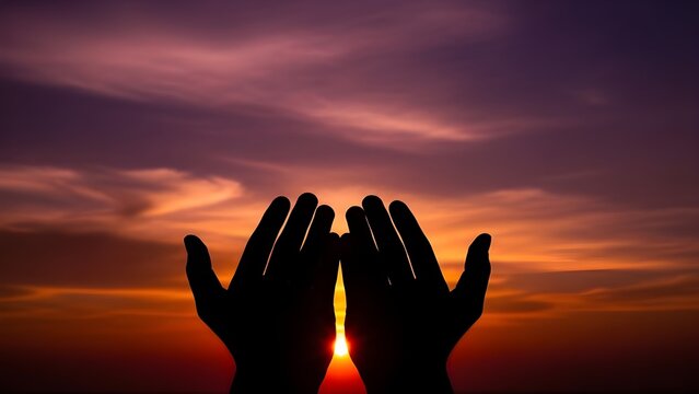 Silhouette of Hands Raised in Prayer Against Sunset Sky