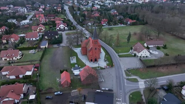 Aerial Osielsko parish church Poland city circle 1. Modern city based on historical Polish architecture. Apartment complex, school, sports fields, parks and individual private residential homes.