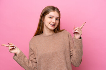Teenager Russian girl isolated on pink background pointing finger to the laterals and happy
