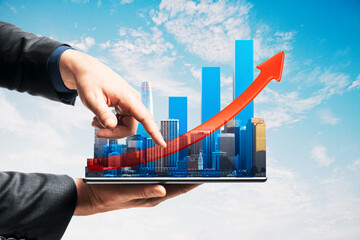 Businessman using tablet with cityscape and growth chart representing real estate market success and digital property investment concept.