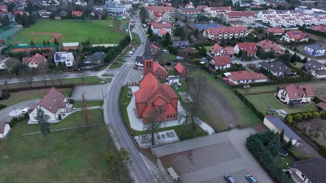 Aerial Osielsko parish church Poland city circle 2. Modern city based on historical Polish architecture. Apartment complex, school, sports fields, parks and individual private residential homes.