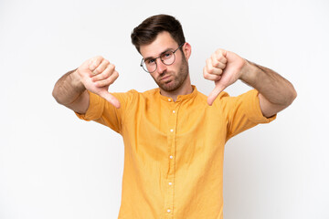 Fototapeta premium Young caucasian man isolated on white background showing thumb down with two hands