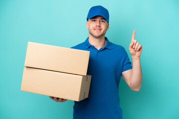 Delivery caucasian man isolated on blue background pointing up a great idea
