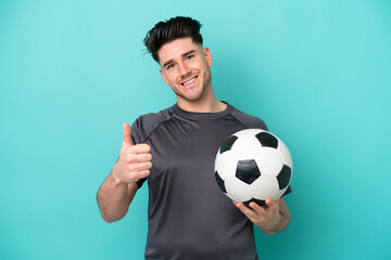 Young caucasian man isolated on blue background with soccer ball and with thumb up