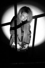 A stylish woman in a coat stands on the stairs. Black and white noir style.