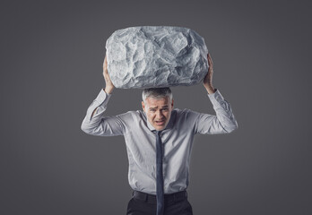 A Businessman Struggling to Hold a Heavy Boulder Above His Head