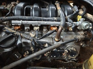 High-Angle Close-up of a Dusty and Greasy Car Engine Bay with Visible Wires, Hoses, and Fuel Injectors, Representing Automotive Engineering, Mechanical Repair, and Vehicle Maintenance