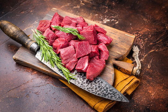 Diced Raw Venison meat, fresh Wild Roe Deer Game Meat on butcher cutting board. brown background. top view