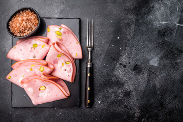 Mortadella Bolognese sausage slices with pistachios. black background. top view