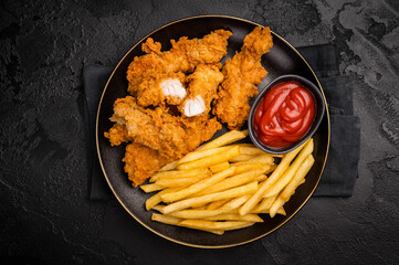 Deep fried chicken strips, sticks with french fry and sauce. black background. top view