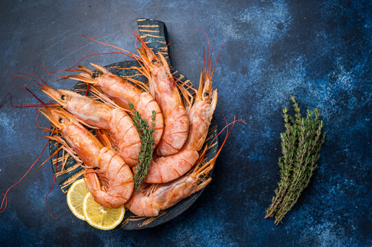 Ready for cooking Red Argentine shrimps, raw Prawns Langostino Austral on wooden board. blue background. top view