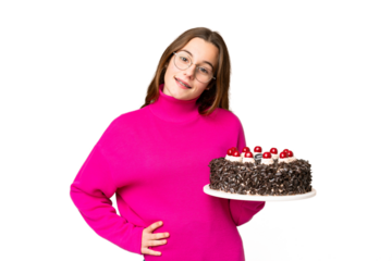 Teenager girl holding birthday cake over isolated chroma key background posing with arms at hip and smiling